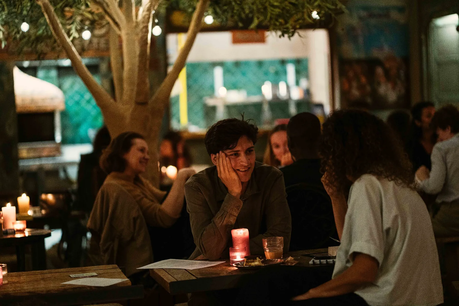 Two participants talk and smile at a table with books and candles.