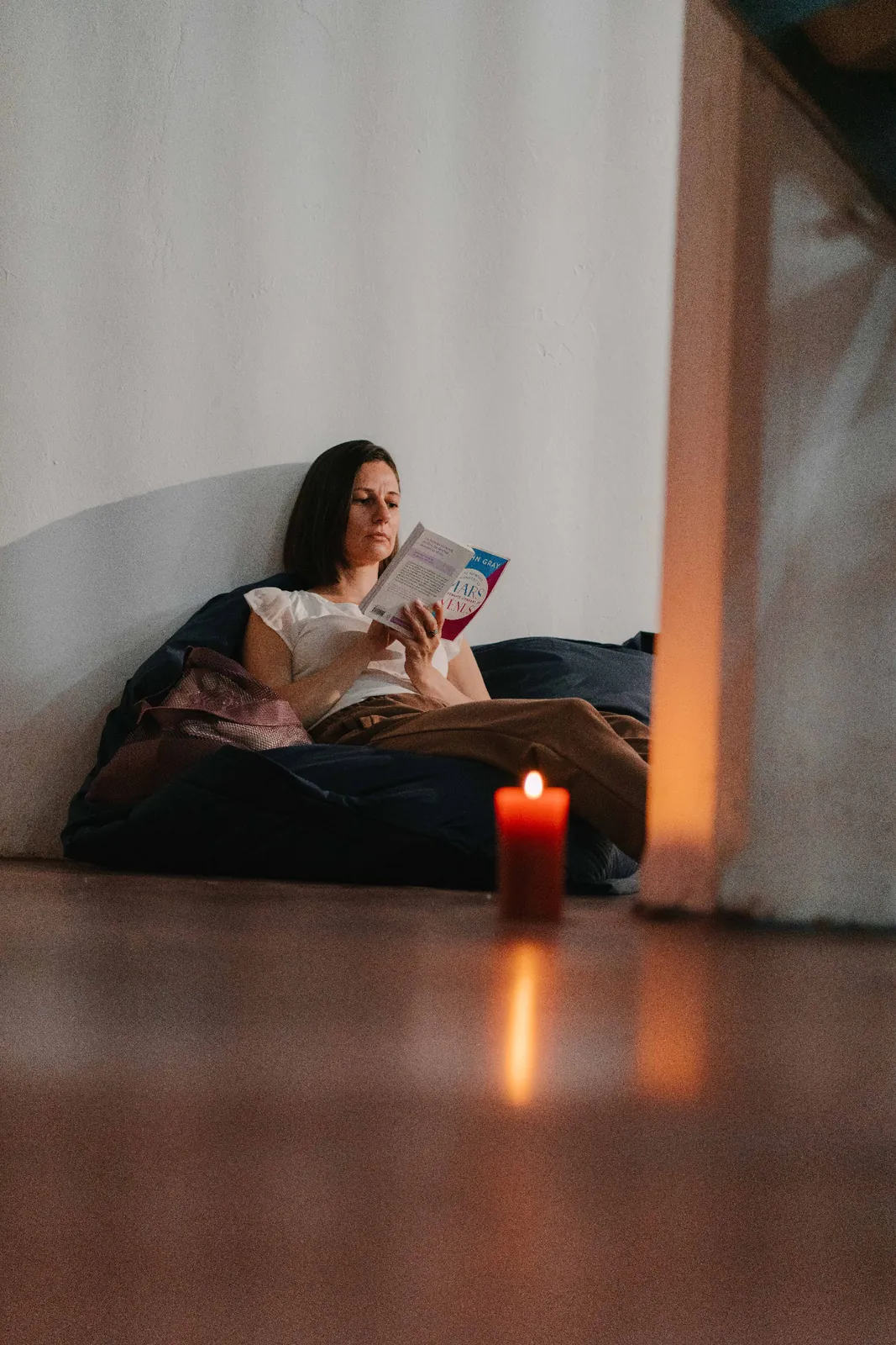 A participant reads on a floor cushion beside a candle.