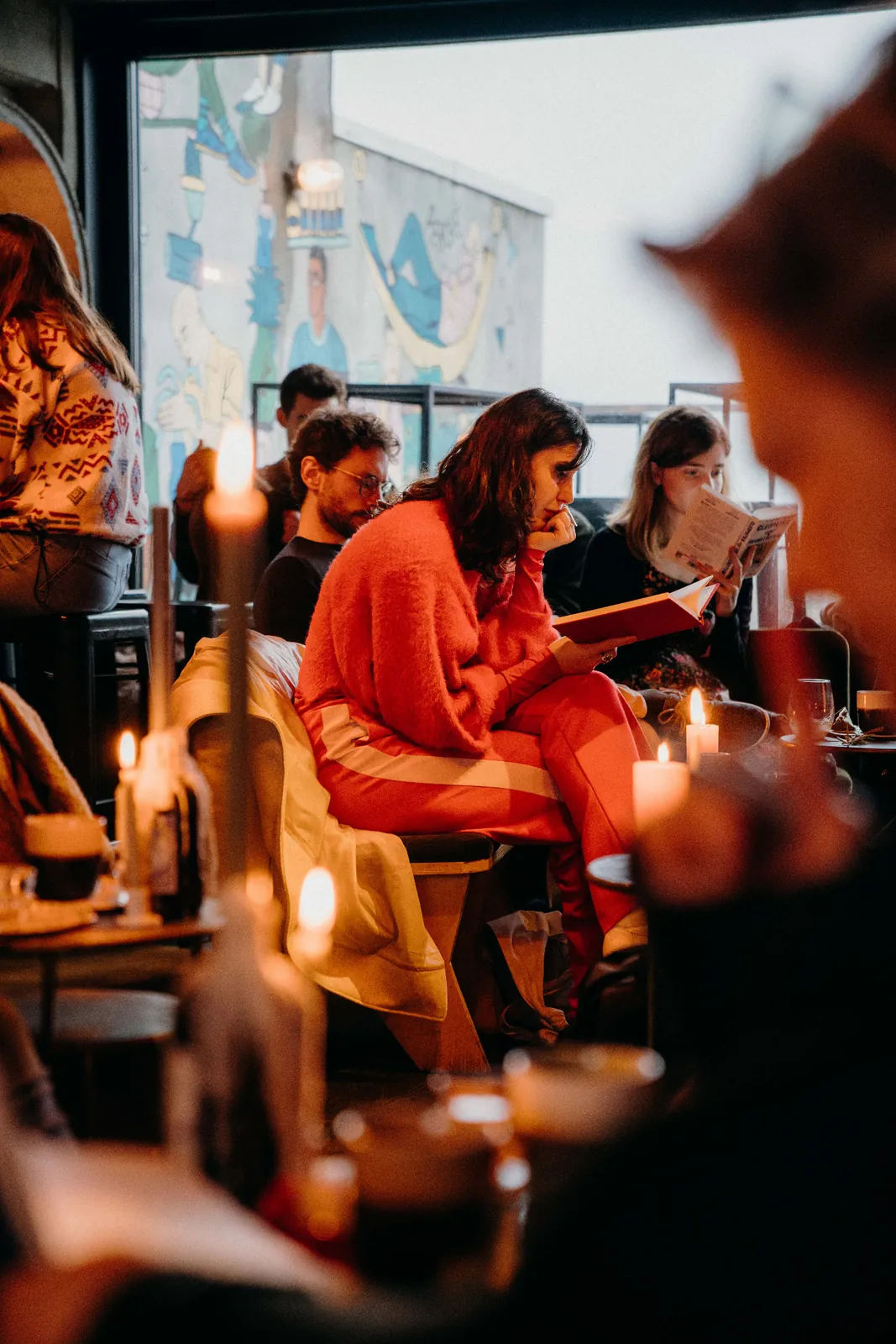 A participant in a red jumper reads among the tables in a bar.