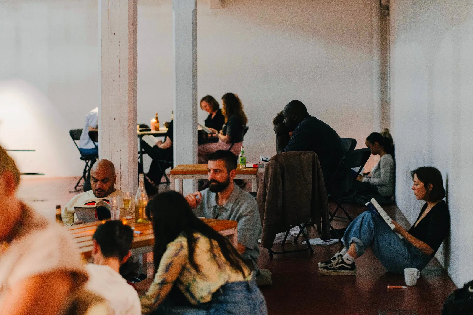 People read in a bright room, seated on the floor and on chairs.