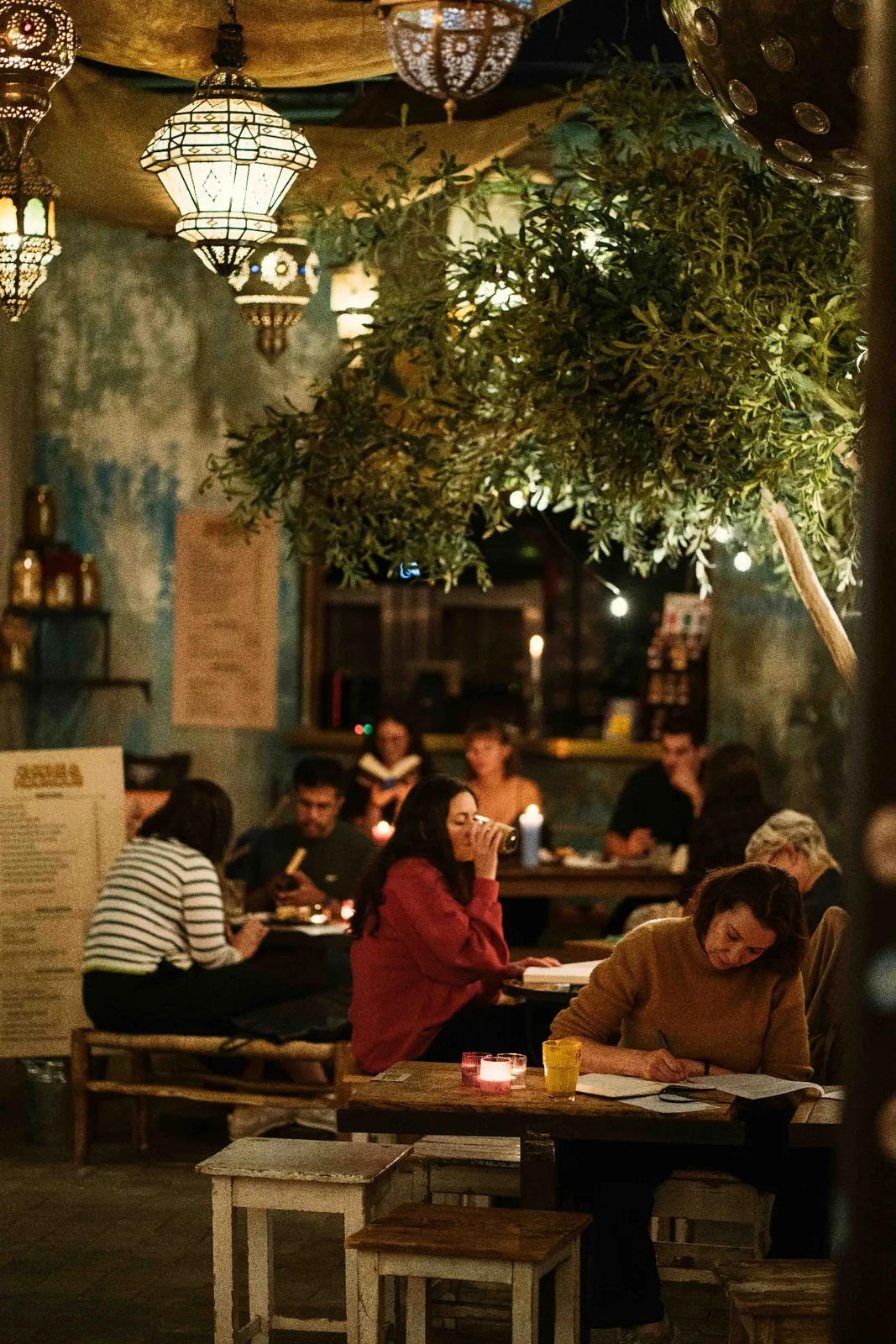 Participants read in a bar with hanging lamps and plants.